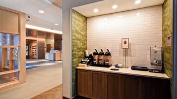 Una estación de café moderna con pared de ladrillo blanco, armarios de madera y una máquina de café.