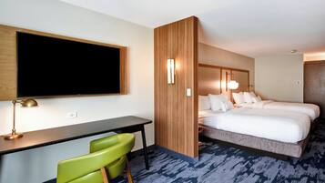 A hotel room with a bed, desk, and green chair.