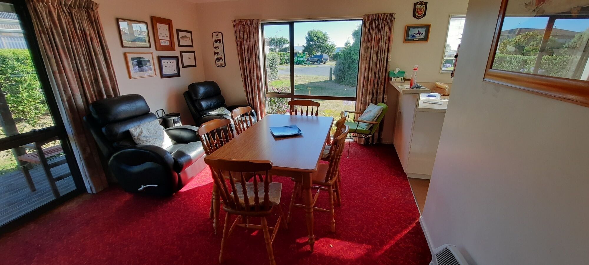 A room with a dining table, chairs, a sofa, and a window with a view of the outside.