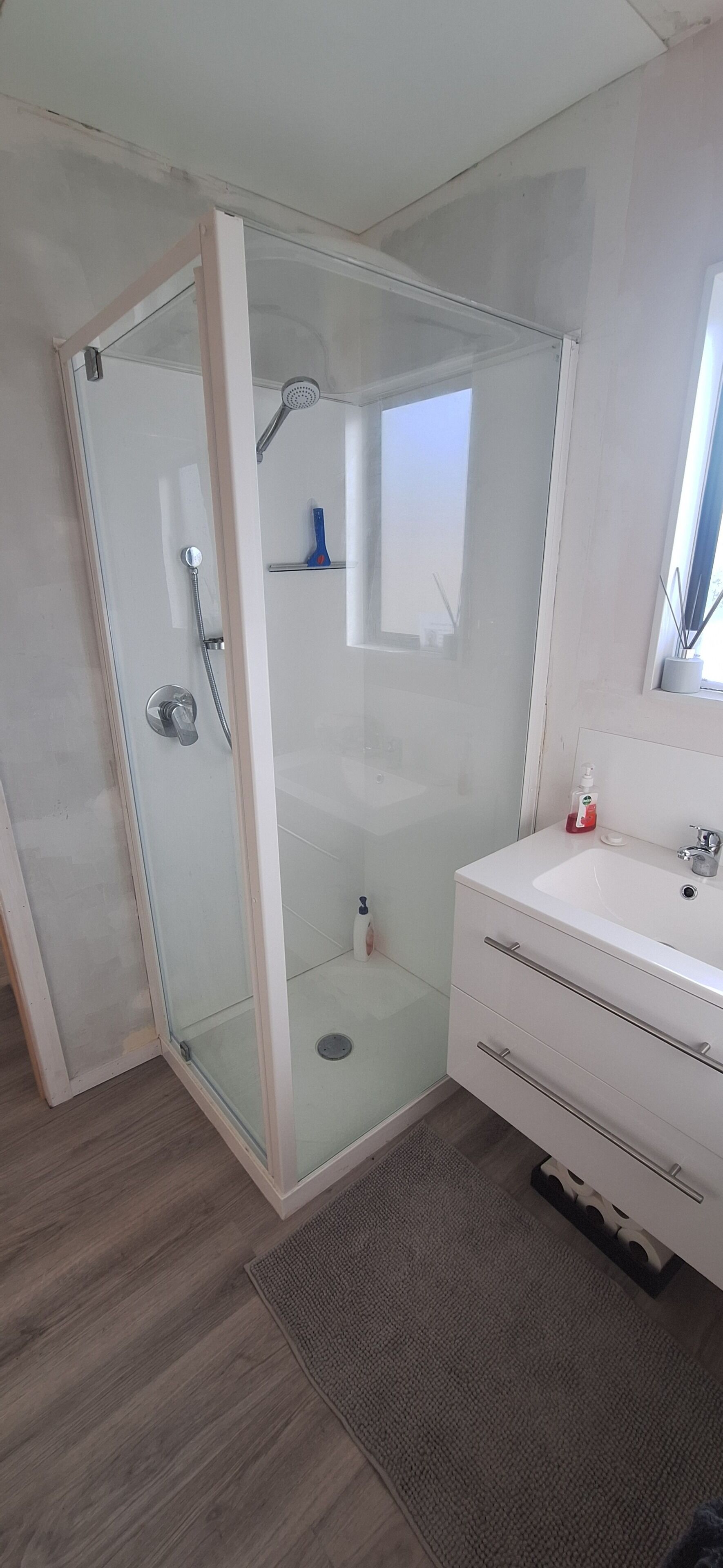 A modern bathroom with a glass-enclosed shower, a white sink, and a mirror above it.