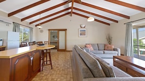 Uma sala de estar acolhedora com um sofá, uma área de jantar com mesa e cadeiras, e uma cozinha com geladeira.