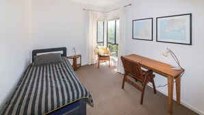 A bedroom with a single bed, a wooden desk, two chairs, a small table with a lamp, and two framed maps on the wall. - 20 Lady Bay Road Normanville (Normanville)