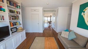 A living room with a bookshelf, a sofa with patterned cushions, and a large painting on the wall. - 20 Lady Bay Road Normanville (Normanville)