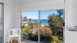 Un balcón con vista al mar, una silla blanca y una zona de cocina con un lavabo.