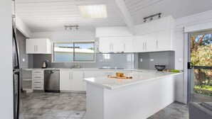 Una cocina moderna con armarios blancos, una isla central y vistas al exterior.