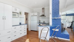 Una cocina moderna con armarios blancos, una pared de acento azul y una isla integrada con taburetes.