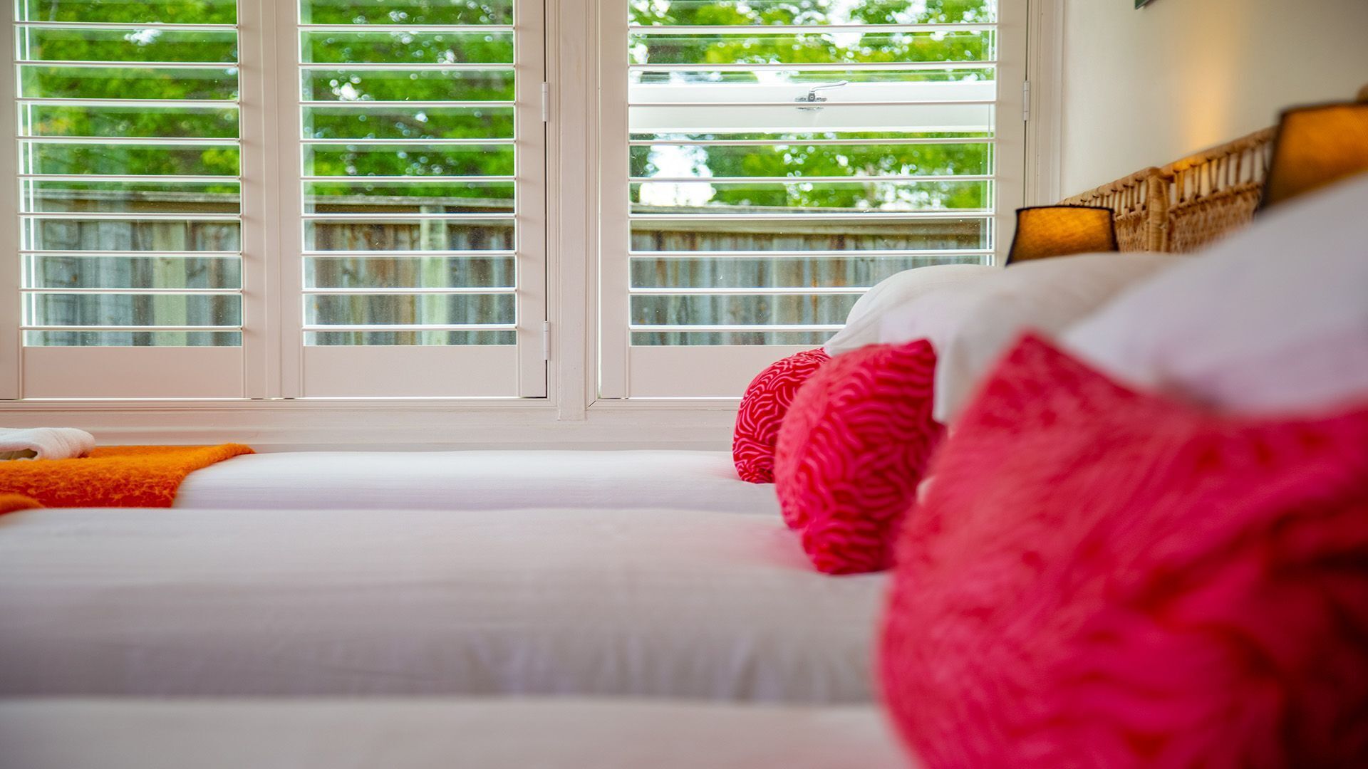 Une chambre d’hôtel avec une grande fenêtre, un lit avec du linge de lit blanc et une vue sur la verdure.