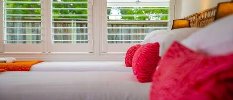 Une chambre d’hôtel avec une grande fenêtre, un lit avec du linge de lit blanc et une vue sur la verdure.