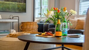 A round table with a bottle of champagne, two glasses, a fruit platter, and a vase of flowers. - Amber Cottage - country cottage (Bowral)