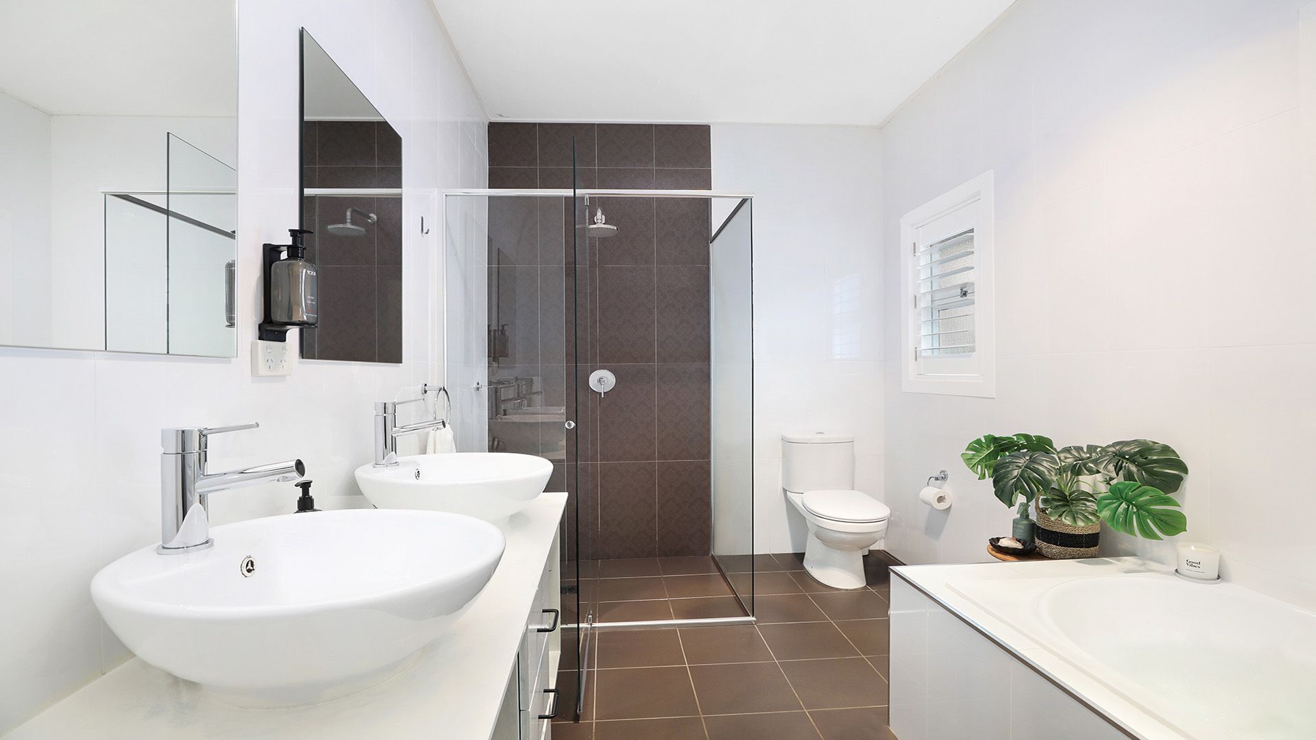 Un baño moderno con dos lavamanos, un inodoro y una zona de ducha.