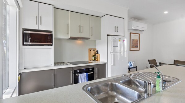 A modern kitchen with stainless steel appliances, a built-in oven, and a double sink. - Bungala Cottage - 28 Jetty Road (Normanville)