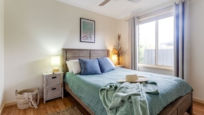 A bedroom with a bed, bedside tables, a lamp, a picture on the wall, and a window with curtains.