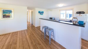 Een keuken met een centraal eiland, twee krukken, een magnetron en een koelkast.