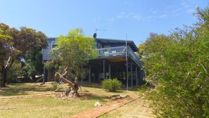 A two-story house with a balcony, surrounded by trees and a grassy yard. - Tree Top - 4 Robert Norman Street (NORMANVILLE)