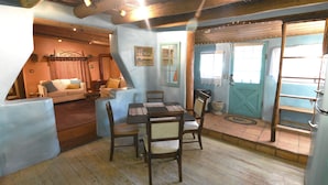 A cozy room with a wooden dining table, chairs, a sofa, and a staircase leading to another level. - Peaceful Adobe w Jacuzzi, Walk To Arroyo Seco, Pets Welcome (Arroyo Seco)