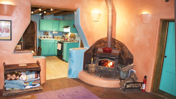 A cozy kitchen with teal cabinets, a stone fireplace, and a wooden ceiling. - Peaceful Adobe w Jacuzzi, Walk To Arroyo Seco, Pets Welcome (Arroyo Seco)