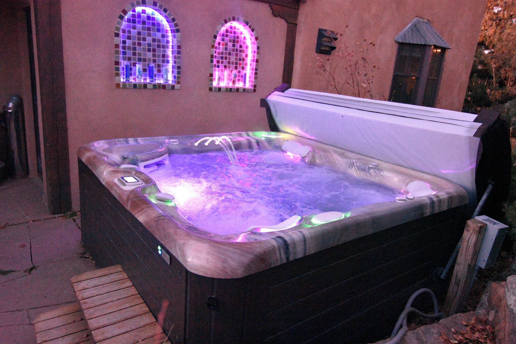 A hot tub with a control panel and a wooden deck in front.