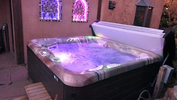 A hot tub with a control panel and a wooden deck in front.