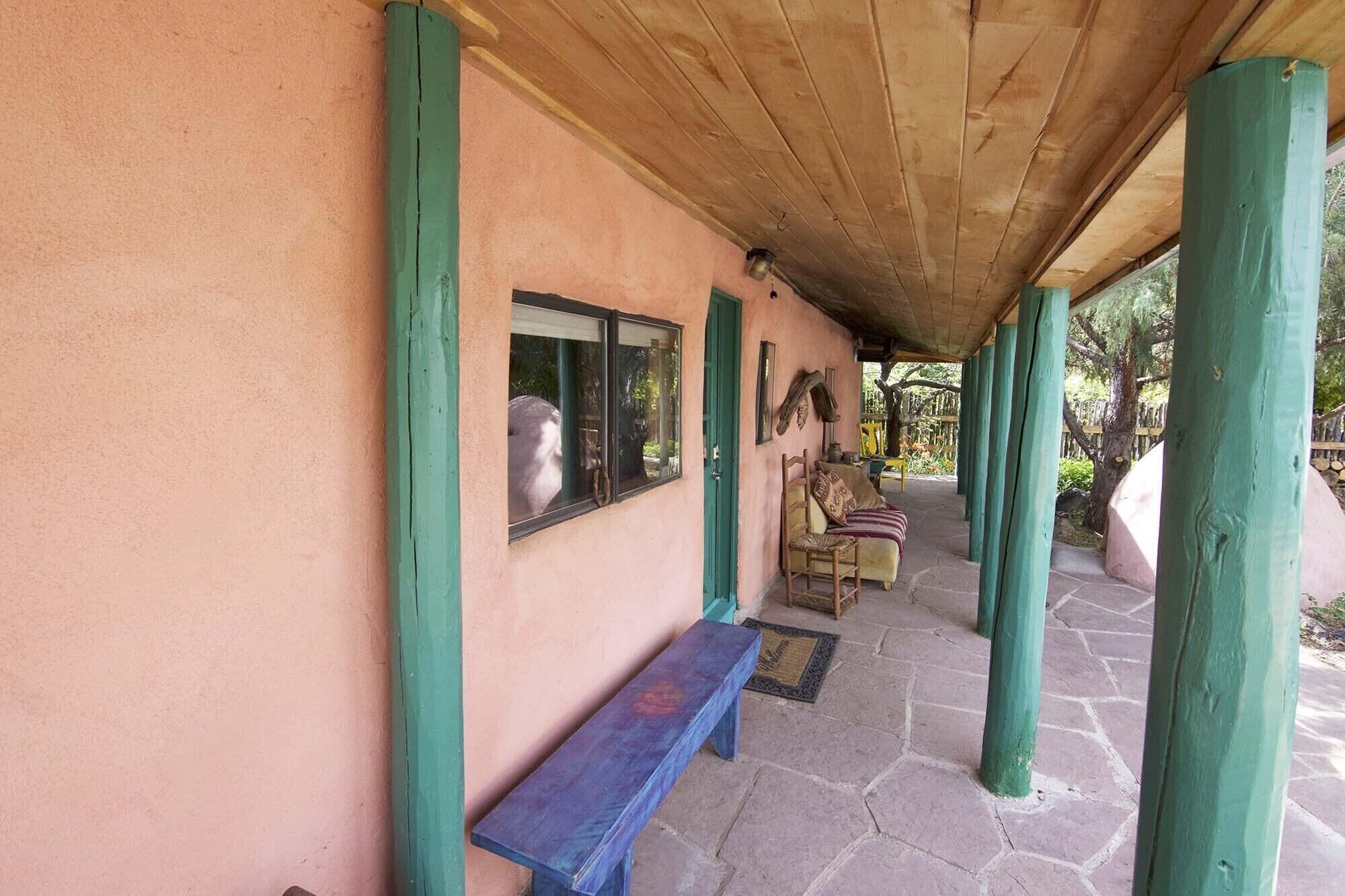 A covered porch with a bench, a chair, and a table.