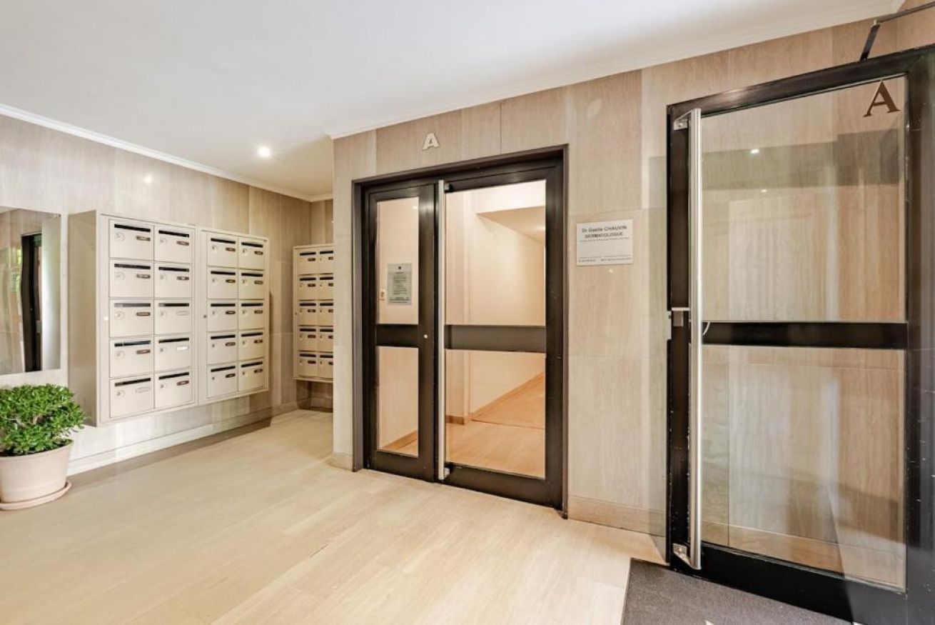 A hotel lobby with a reception desk, a plant, and a set of lockers.