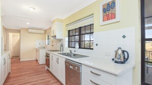 A modern kitchen with white cabinetry, a dishwasher, and a large window. - By the Beach - 30 Jetty Road (Normanville)
