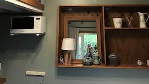 Una cocina con una escalera de madera, un microondas, un espejo y una repisa con adornos.