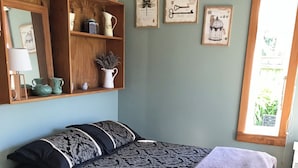 Un dormitorio con cama, una estantería de madera con adornos, una ventana con vistas y decoración en la pared.