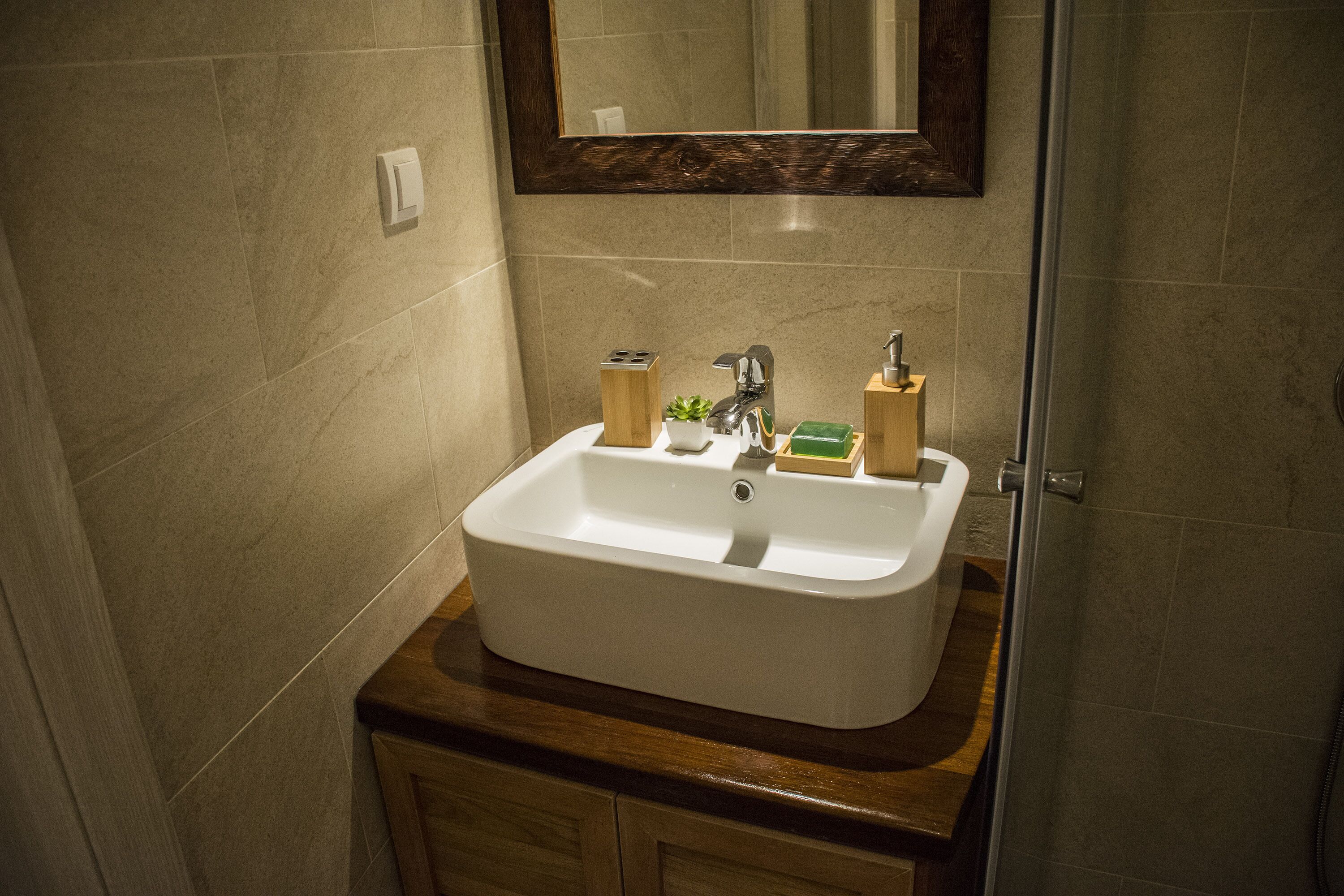 A bathroom with a white sink, wooden countertop, and a mirror above it.