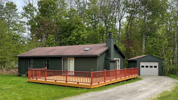 Een chalet met een houten terras en een garage.