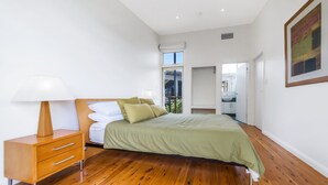 A bedroom with a bed, bedside table, and a window.
