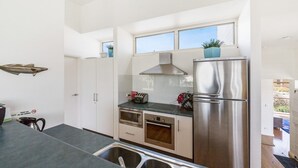 A modern kitchen with stainless steel appliances, a toaster, and a microwave. There are two windows providing natural light and a view of the outside.