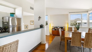 A modern kitchen with a built-in refrigerator and a dining area with wicker chairs and a wooden table.