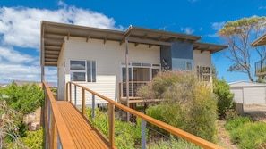 Two-story building with a flat roof and balcony, featuring large windows and a wooden deck.