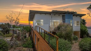 A two-story house with a wooden deck and a balcony.