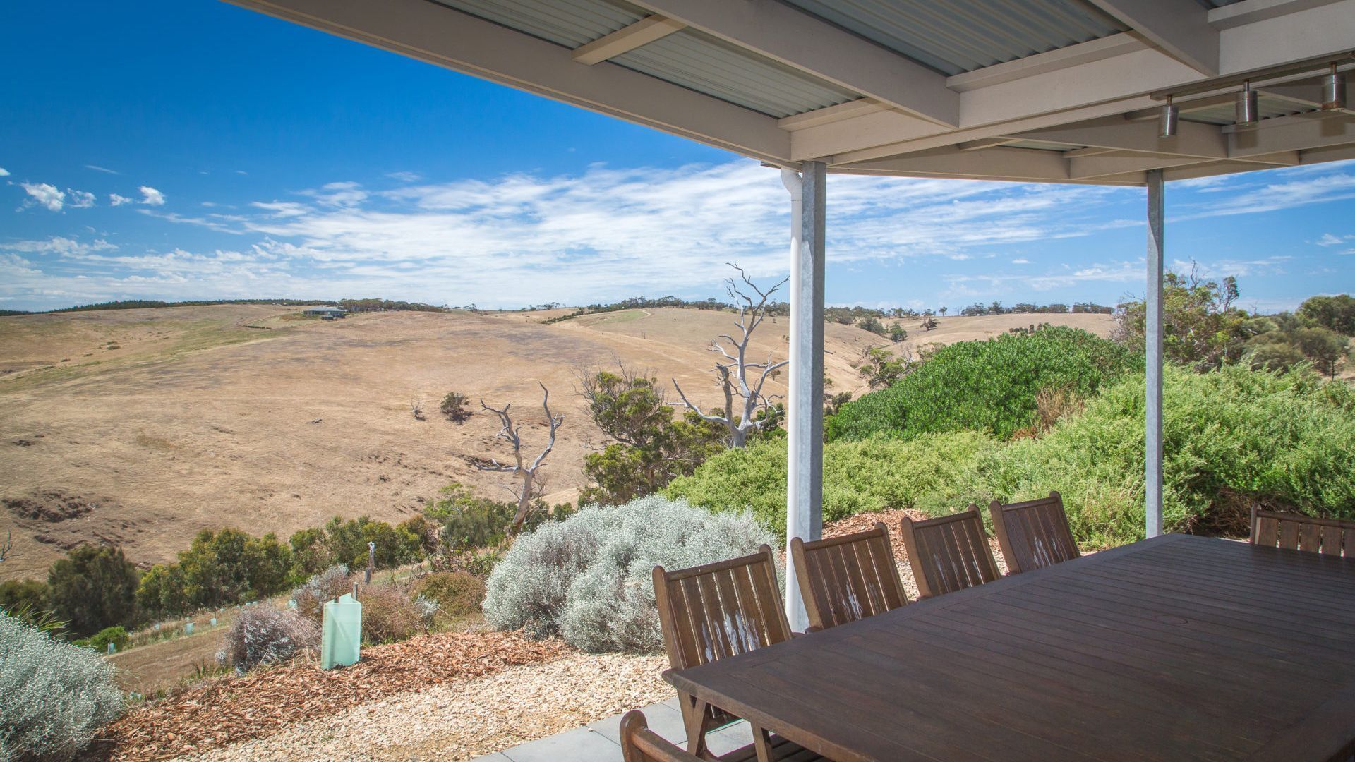 Un espacio de comedor al aire libre cubierto con vistas a un paisaje seco y montañoso.