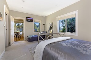 Relax in a spacious bedroom with a large bed, desk area, and wall-mounted TV, offering a view of the outdoors.
