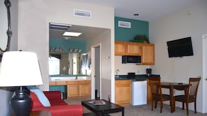 A compact living space with a kitchenette, a dining area, and a red sofa. - Luxury Studio Apartment Located in a Popular High Desert Resort (Green Valley)