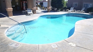 A swimming pool with a pool ladder, lounge chairs, and a Coca-Cola vending machine. - Luxury Studio Apartment Located in a Popular High Desert Resort (Green Valley)