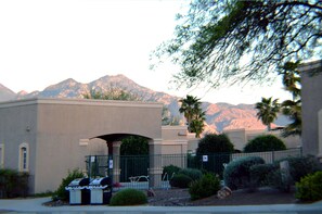 A building with a flat roof, a covered entrance, and a mountain backdrop. - Luxury Studio Apartment Located in a Popular High Desert Resort (Green Valley)
