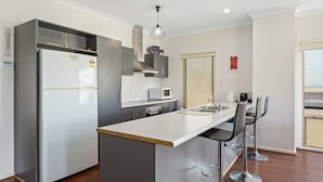 Een moderne keuken met een geïntegreerde koelkast, magnetron en een roestvrijstalen spoelbak.