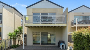 Een woonhuis met twee verdiepingen, een balkon, schuiframen en een kleine hondenhuis.