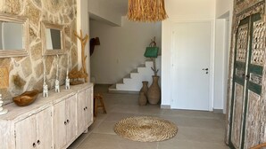 Ein Korridor mit einer Steinwand, einem Holzschrank mit Dekorationen, einem Teppich und einer Treppe sowie einer rustikalen Tür.