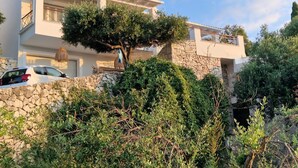 Ein modernes, zweistöckiges Haus mit einer Steinmauer und einem Baum im Vordergrund.