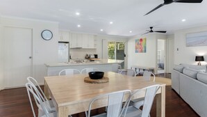 Une cuisine moderne avec des meubles blancs, une table à manger avec des chaises et un ventilateur de plafond.