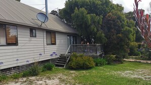 Une maison de plain-pied avec une antenne parabolique, un petit porche et une cour gazonnée.