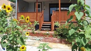 A house with a porch, a front door, and a small garden with sunflowers. - Fremantle South Beach House + Outdoor Studio 4x2 (South Fremantle)