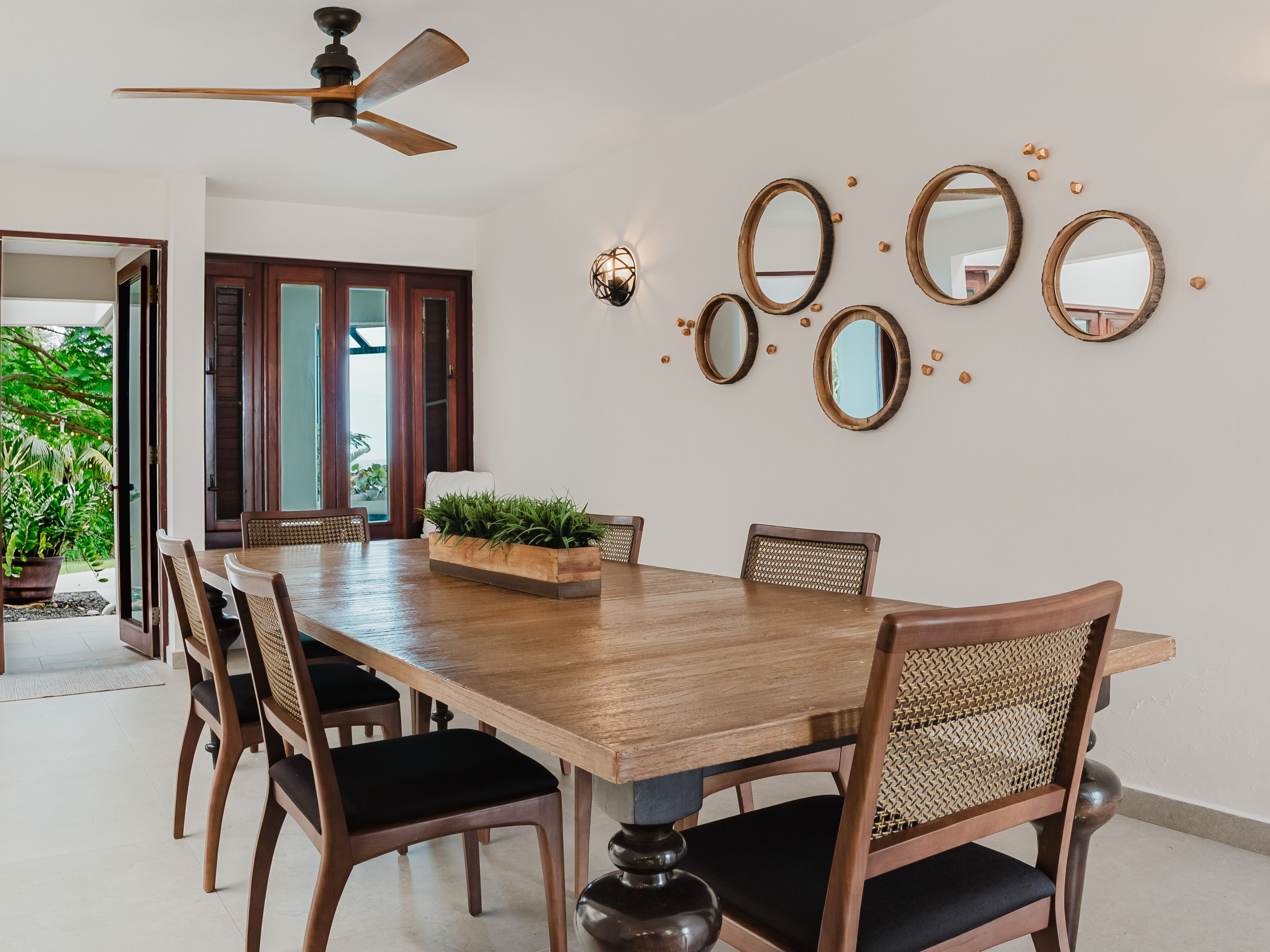 A dining area with a wooden table, chairs, and a ceiling fan.