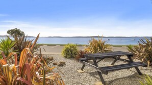 A beachside seating area with a view of the sea and boats. - Apartments at the beach (Blackmans Bay)