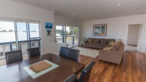 Un salon moderne avec un coin repas, de grandes fenêtres et un balcon.