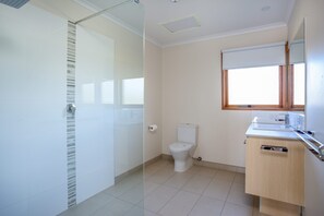 A modern bathroom with a glass shower enclosure, a toilet, and a wooden vanity with a mirror. - BAYSIDE BLISS | BEACH & SPECTACULAR VIEWS | SLEEPS UP TO 12 | RYE (Rye)